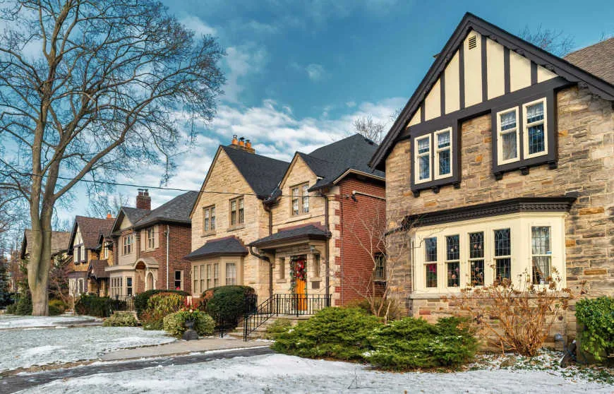 Row of traditional stone and brick houses in a quiet Toronto neighborhood during winter, often chosen by families relocating to toronto.