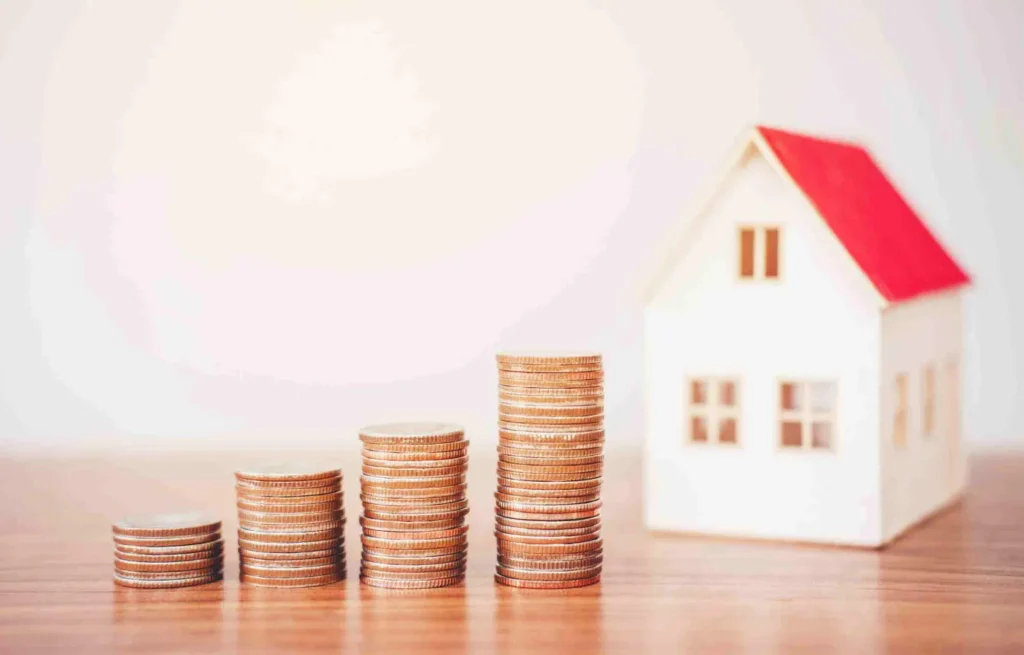 Stacked coins increasing in height beside a small model house, symbolizing rising real estate costs in a Nashville relocation guide.
