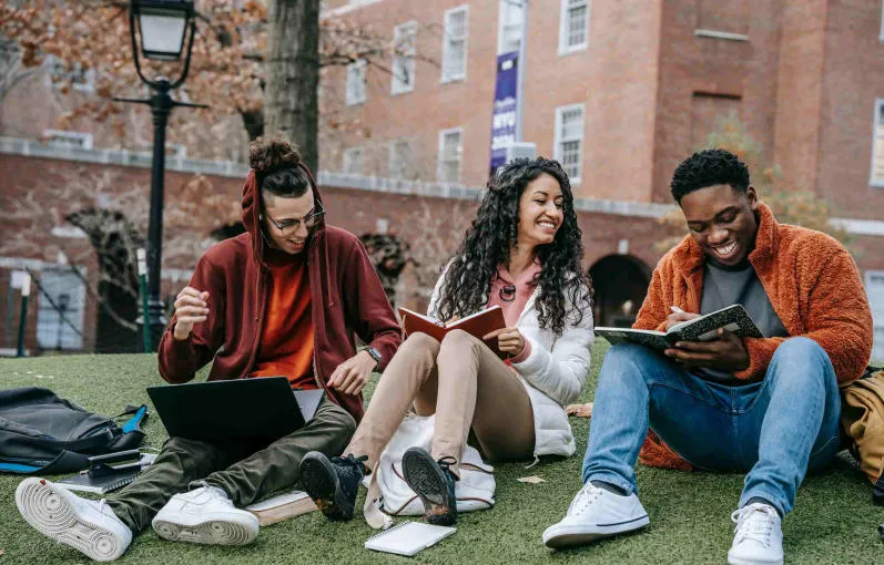 Students sitting together on campus grass, studying and socializing, representing the vibrant student life.