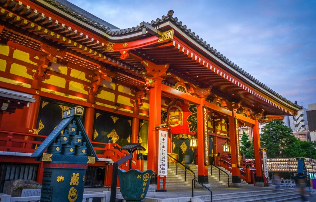 Colorful entrance of a traditional temple in Tokyo, Japan, illuminated at dusk with red pillars and lanterns, representing one of the safest cities in the world 2025.