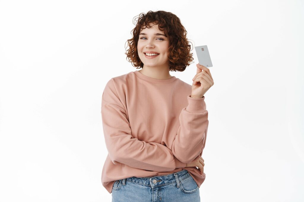 A smiling woman holding a credit card symbolizing credit card referral bonuses.