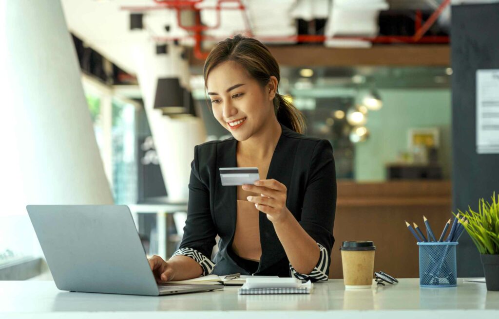 Woman using a laptop with a credit card, checking how much are Chase Ink points worth for rewards.