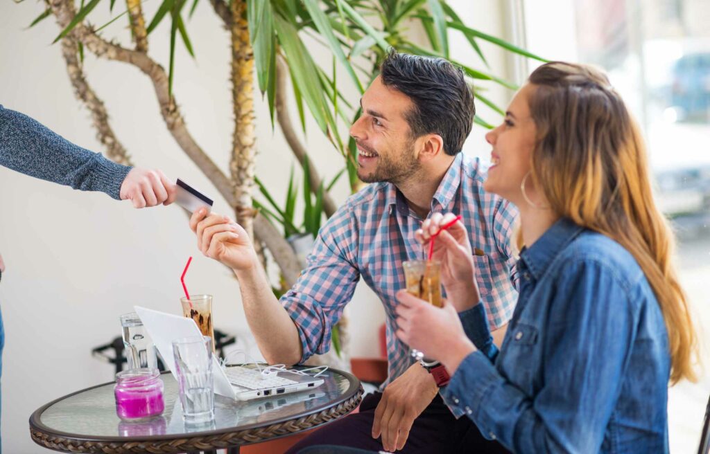 Couple paying with a credit card at a café, showing how much are Chase Ink points worth in daily spending.