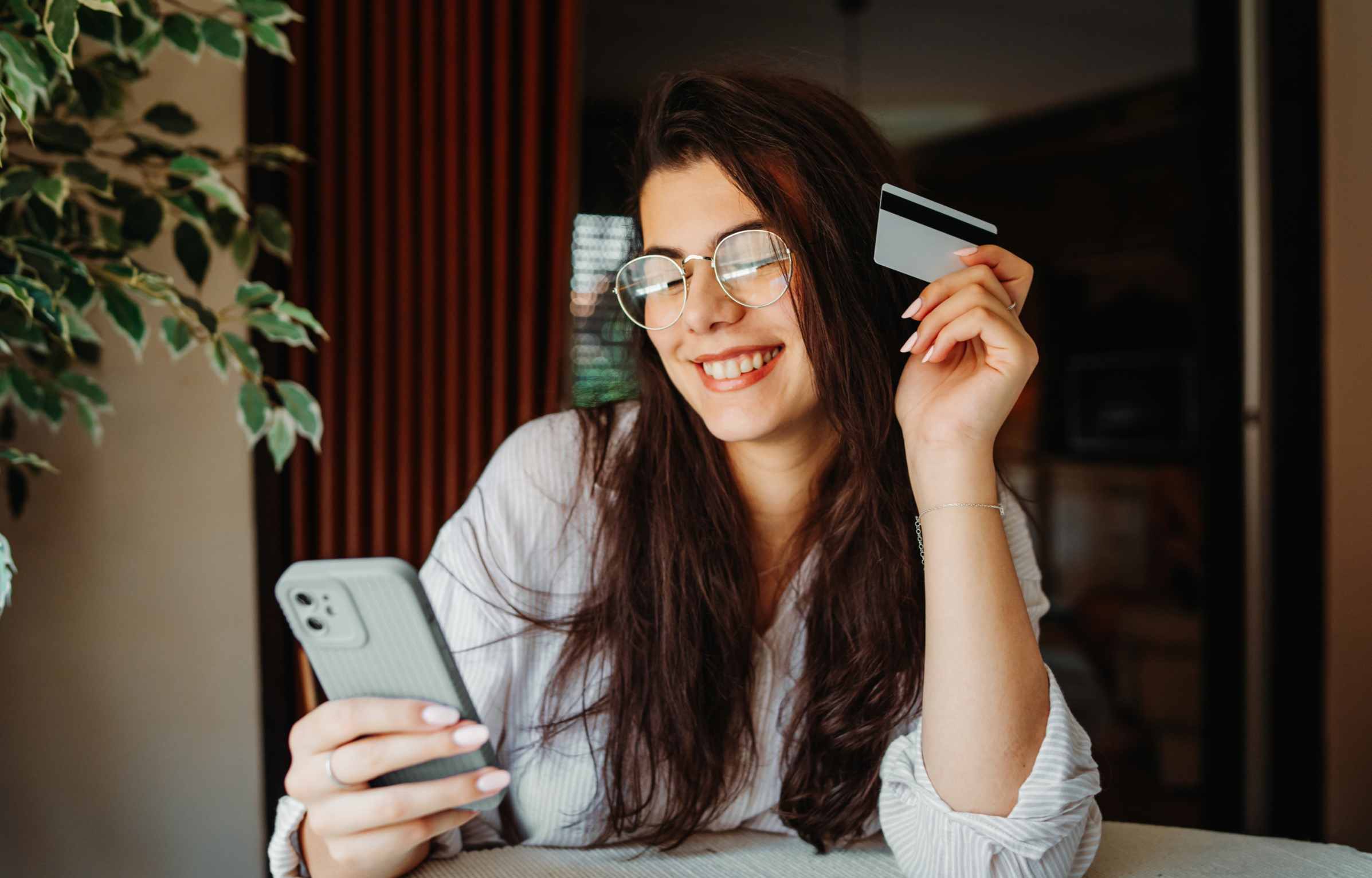 Happy girl using phone and holding credit card