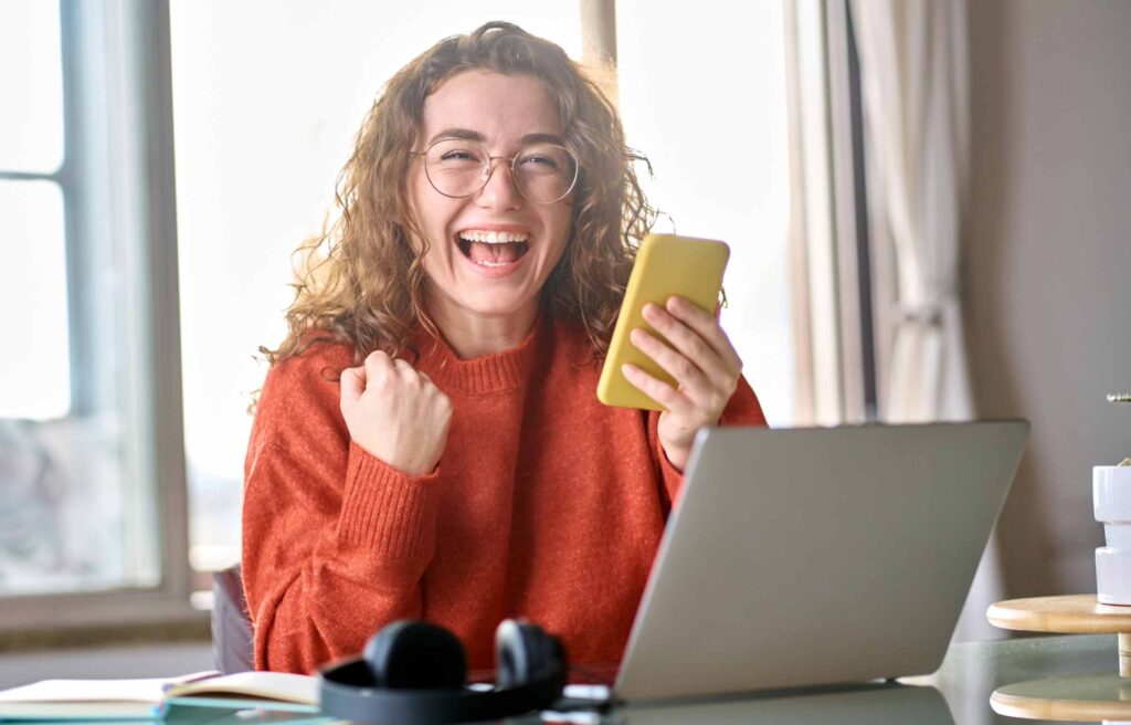 Excited Girl Using Phone and Laptop