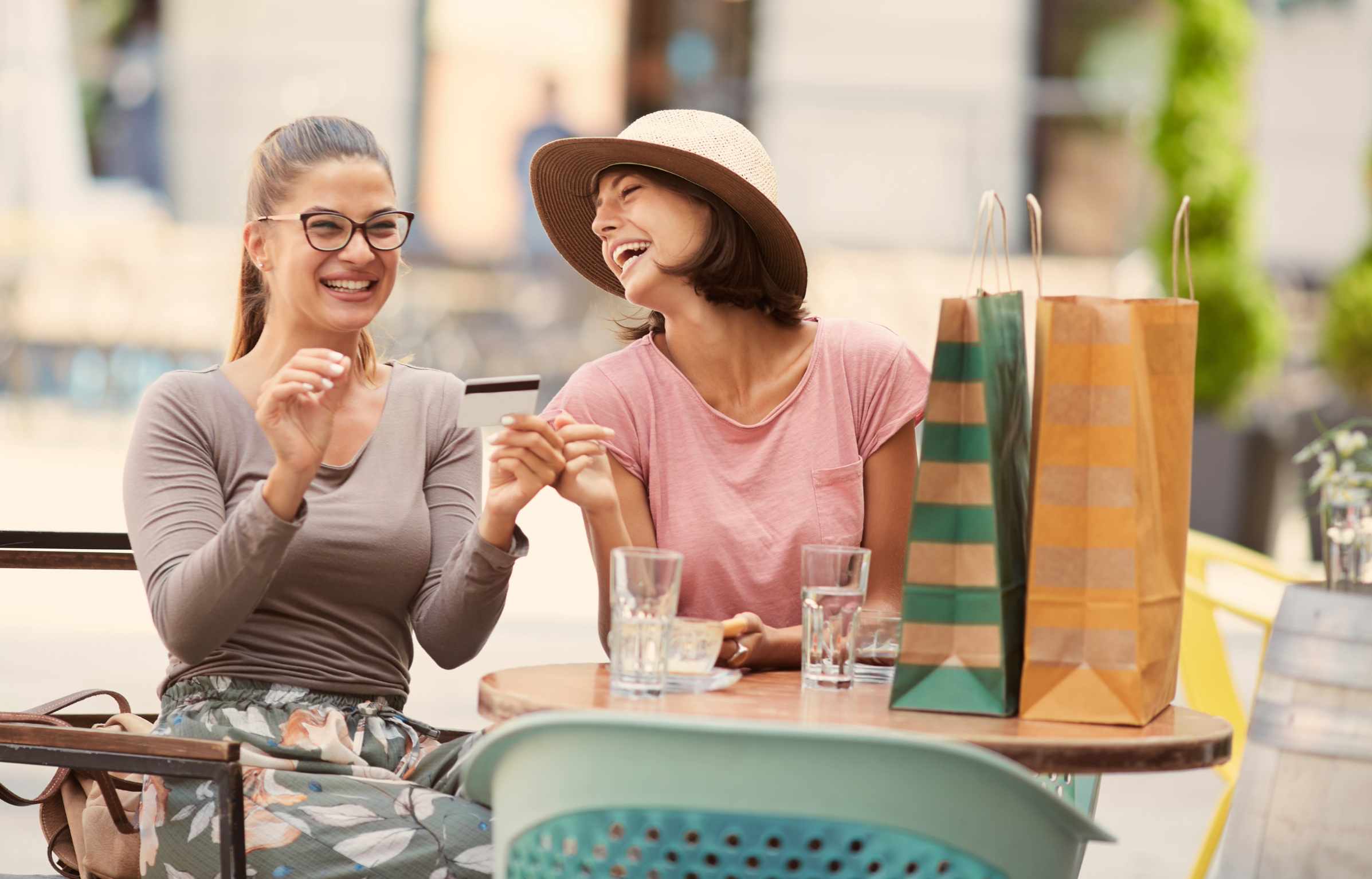 Two happy young woman holding a credit card while smiling