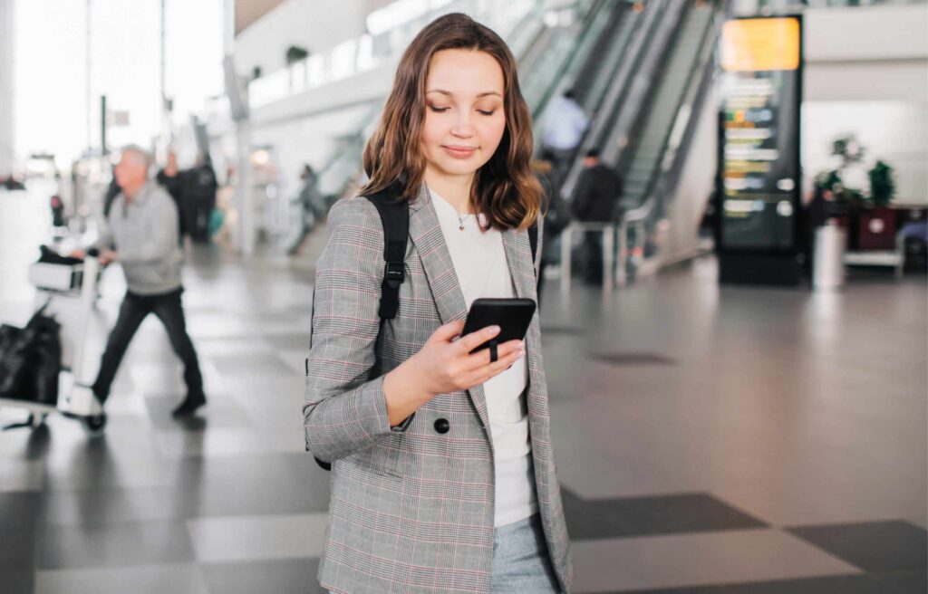 Women at Airprot Using Phone with Luggage