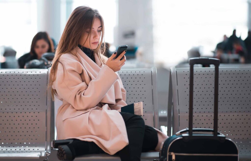 Women waiting at Airprot Using Phone with Luggage