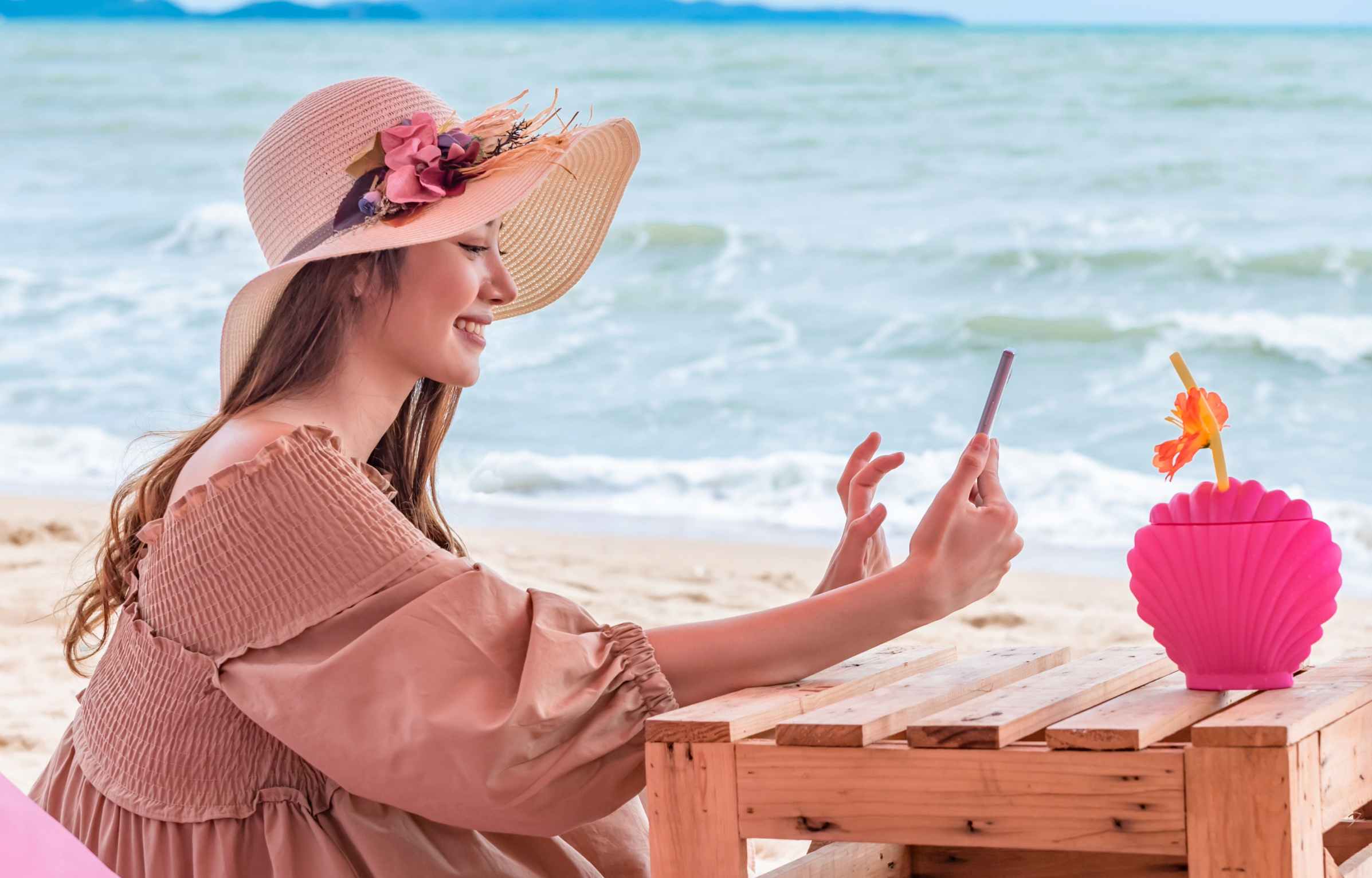 Hat Girl Using Phone on Beach