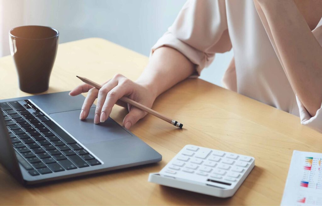 Business woman using computer to review balance sheet annual using document and calculator to calculating budget