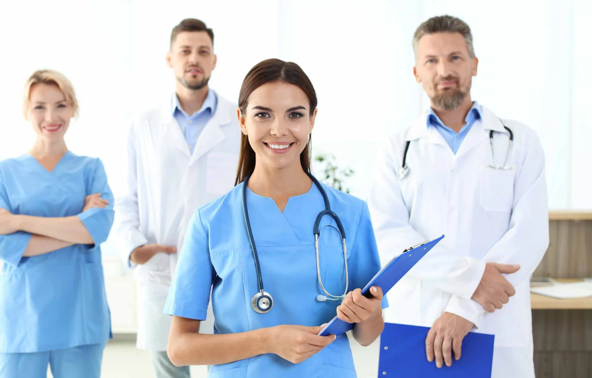 Medical team standing together in a clinic, nurse holding a clipboard in the foreground.