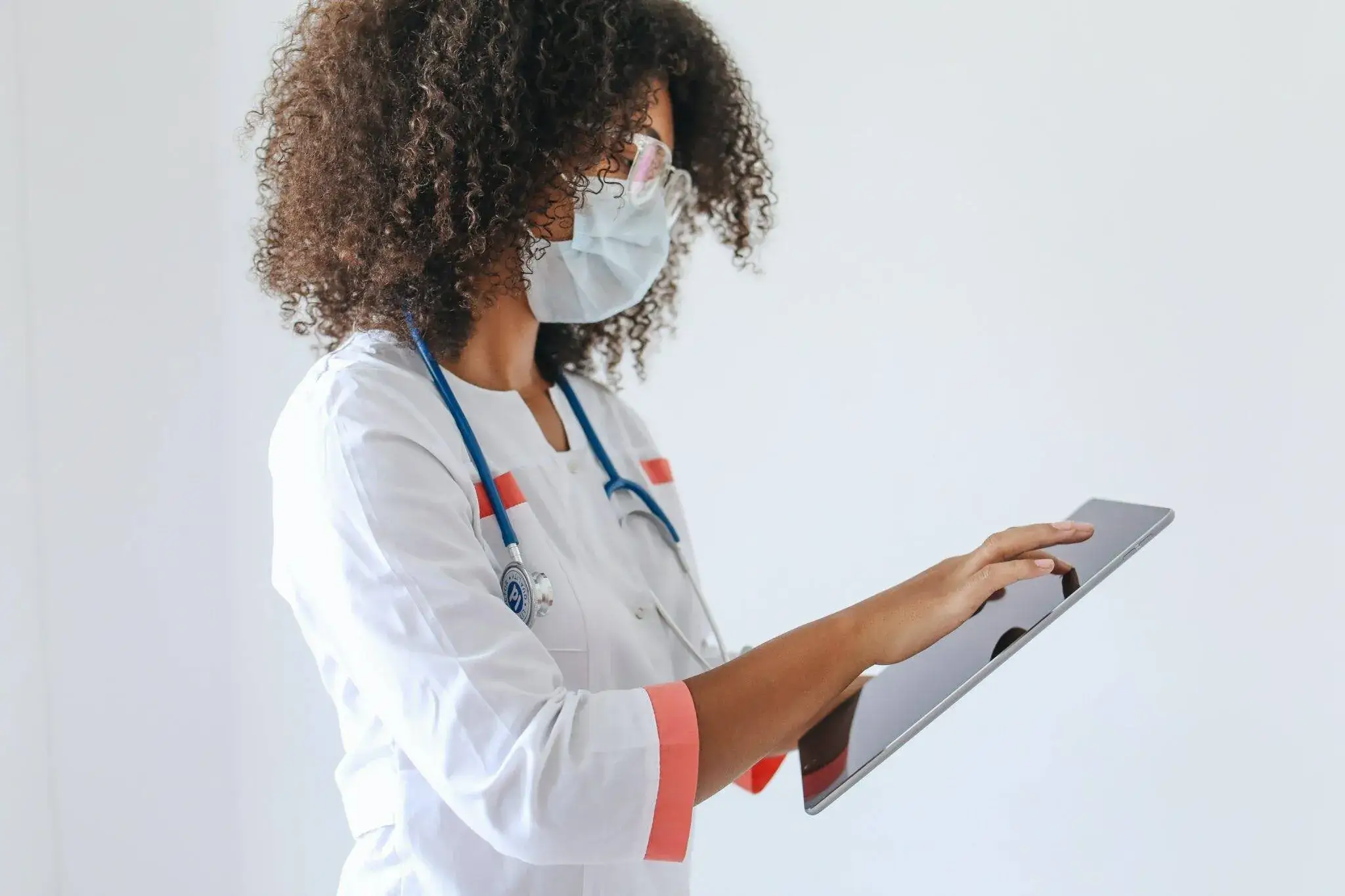 Masked female doctor using tablet for digital medical records