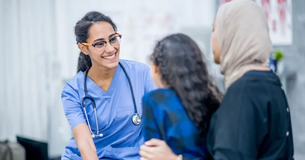 Nurse speaking warmly with a patient and family member during a clinic visit.