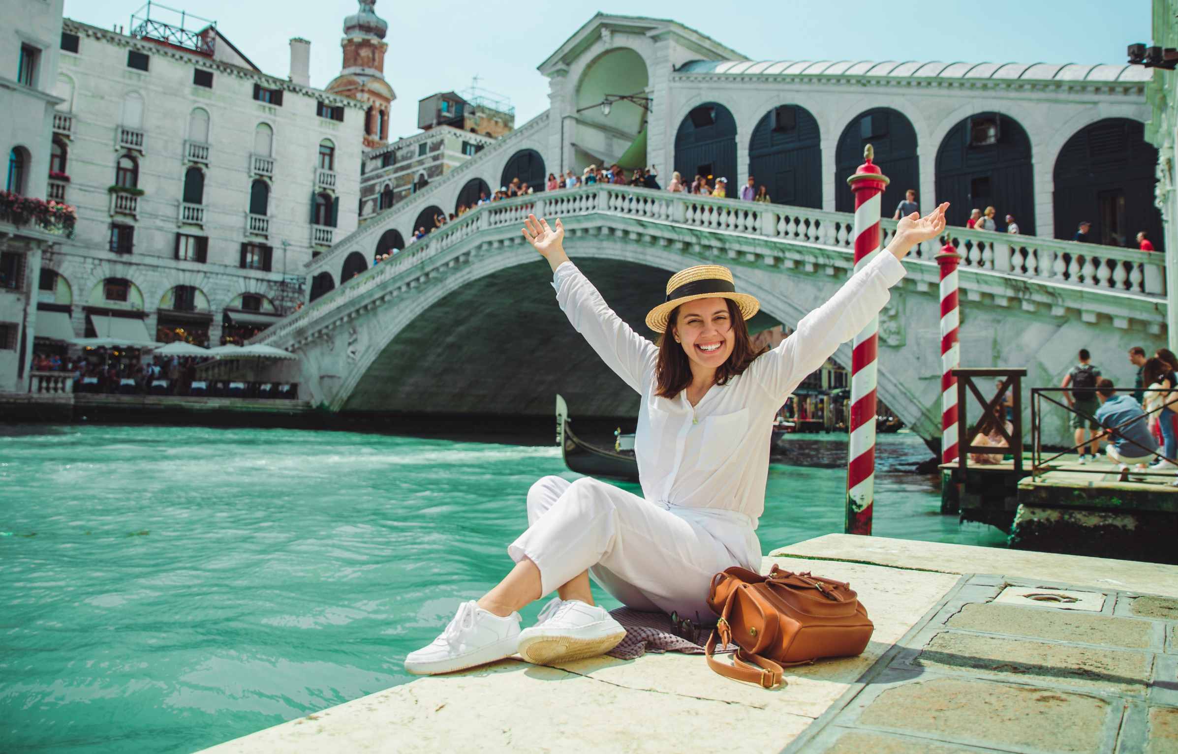 woman sitting near rialto bridge in venice italy looking at grand canal with gondolas