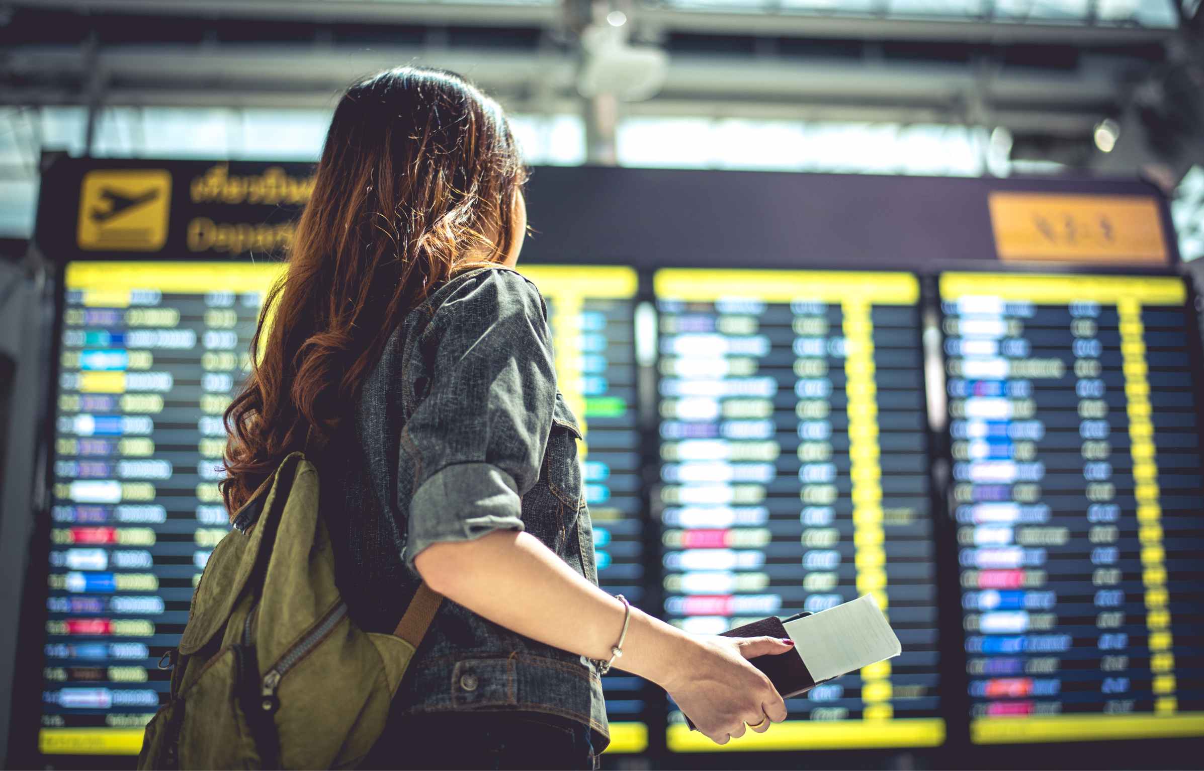 Beauty female tourist looking at flight schedules for checking take off time. People and lifestyles concept. Travel and Happy life of single woman theme. Back view portrait