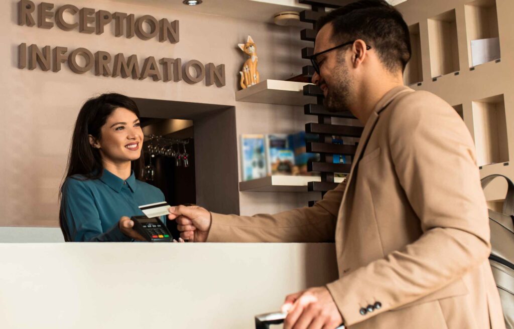 Guest pays for the stay at the hotel to female receptionist with a credit card at the reception