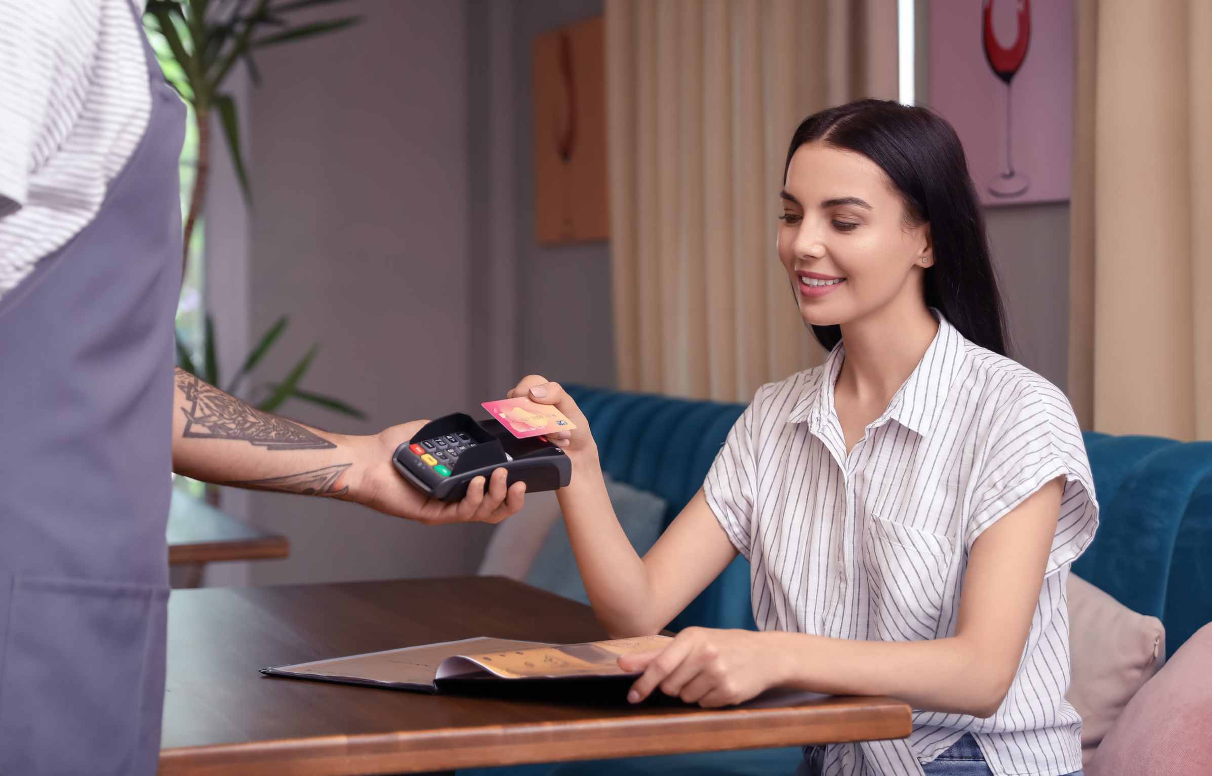 Woman paying bill in restaurant through terminal