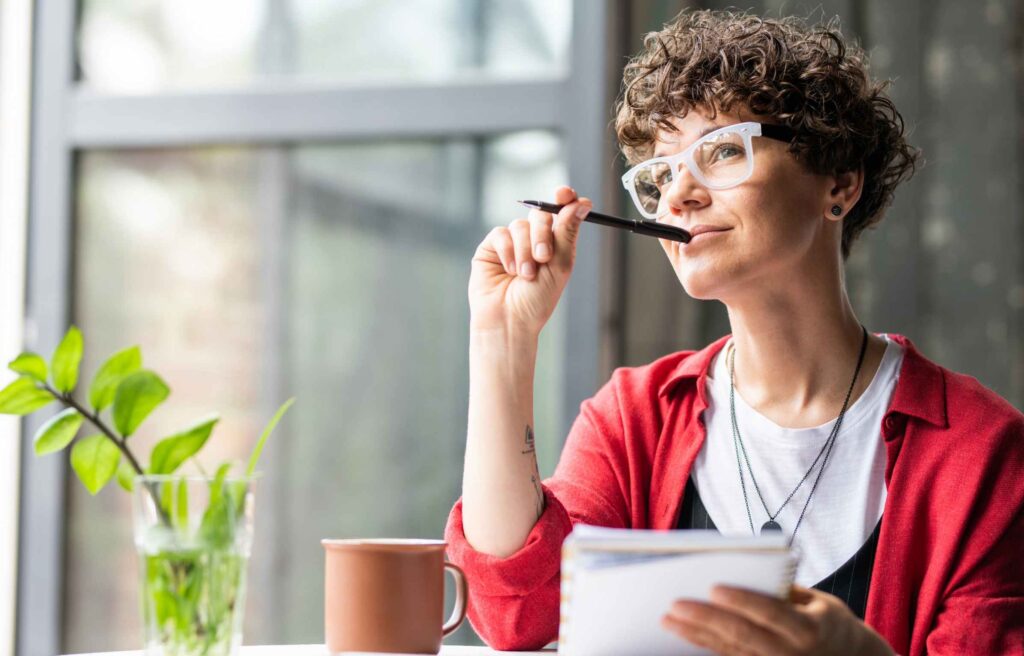 Young pensive female in eyeglasses thinking of new creative ideas