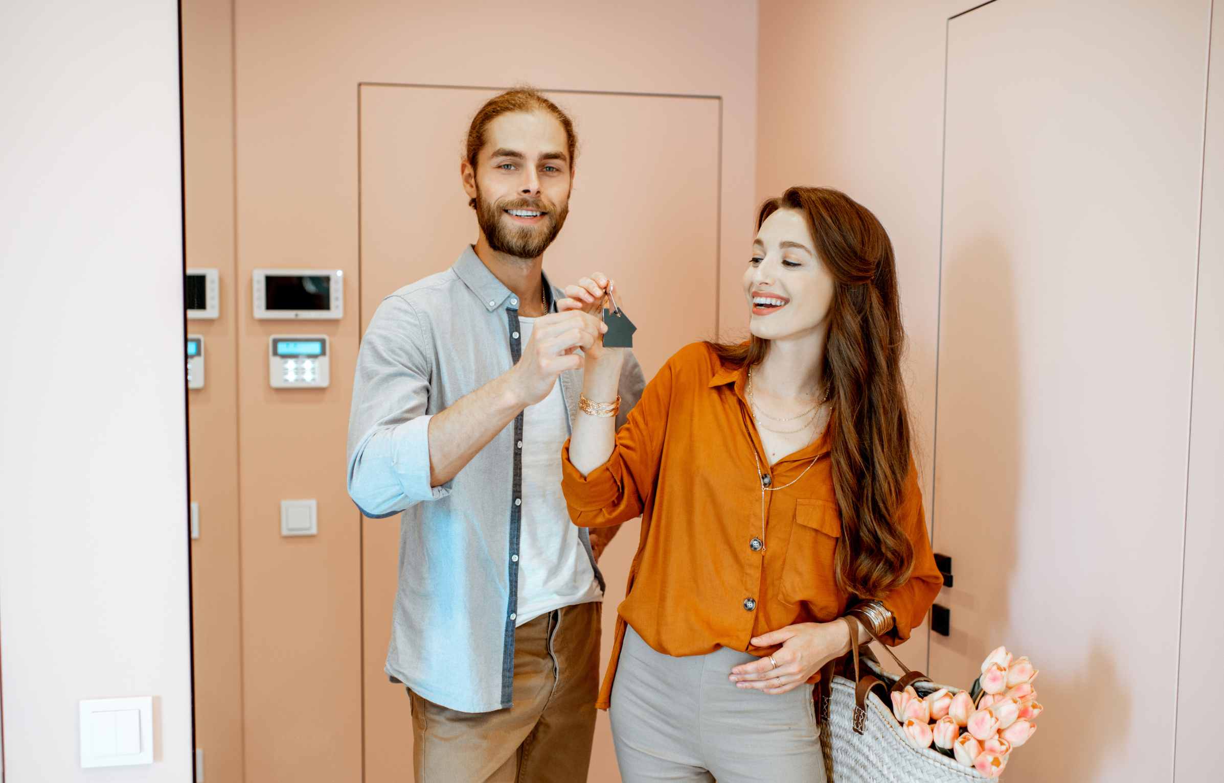 Beautiful young couple coming home, walking together in the pink corridor of the modern apartment