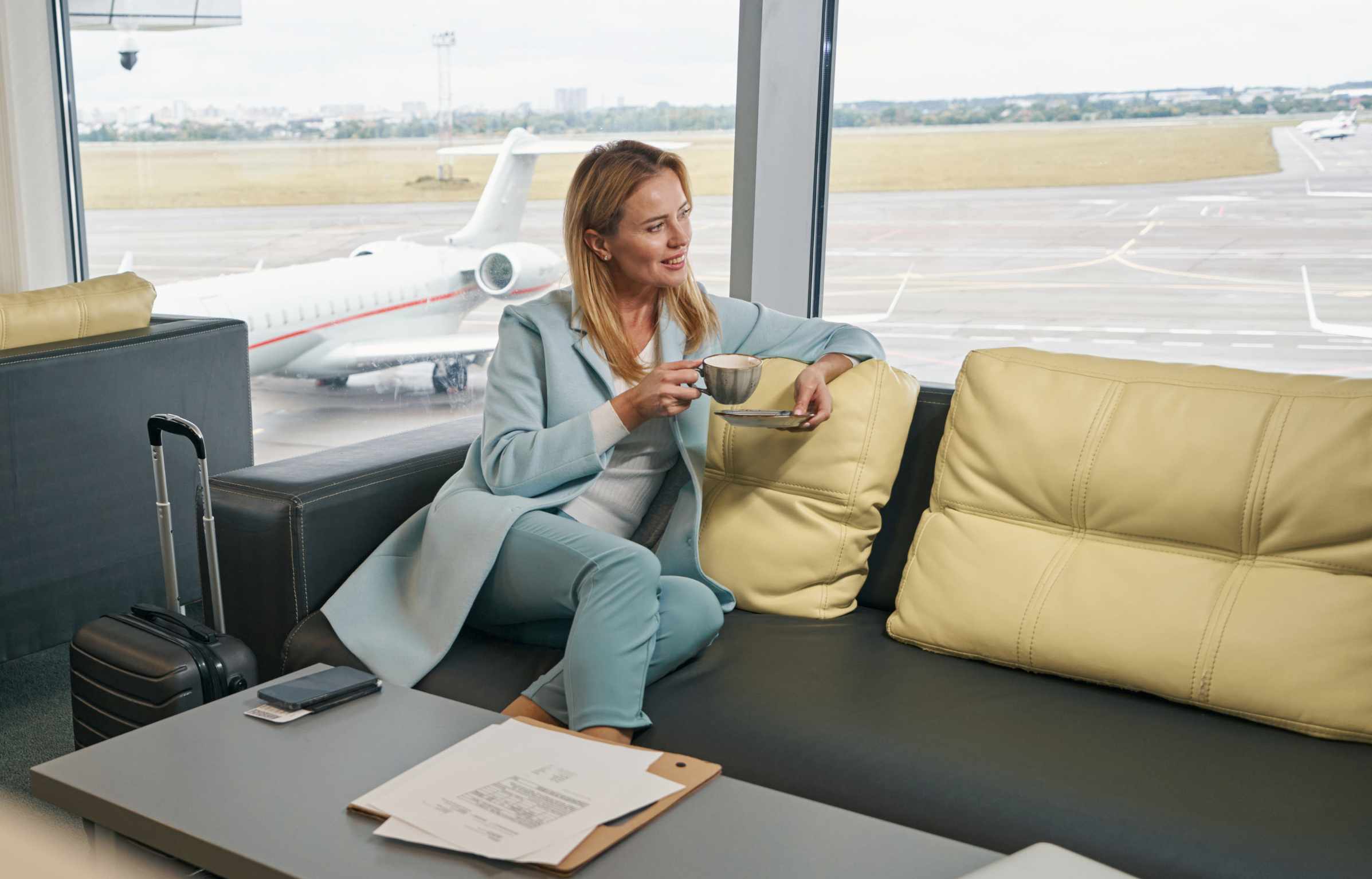 Smiling airline passenger drinking coffee in airport lounge