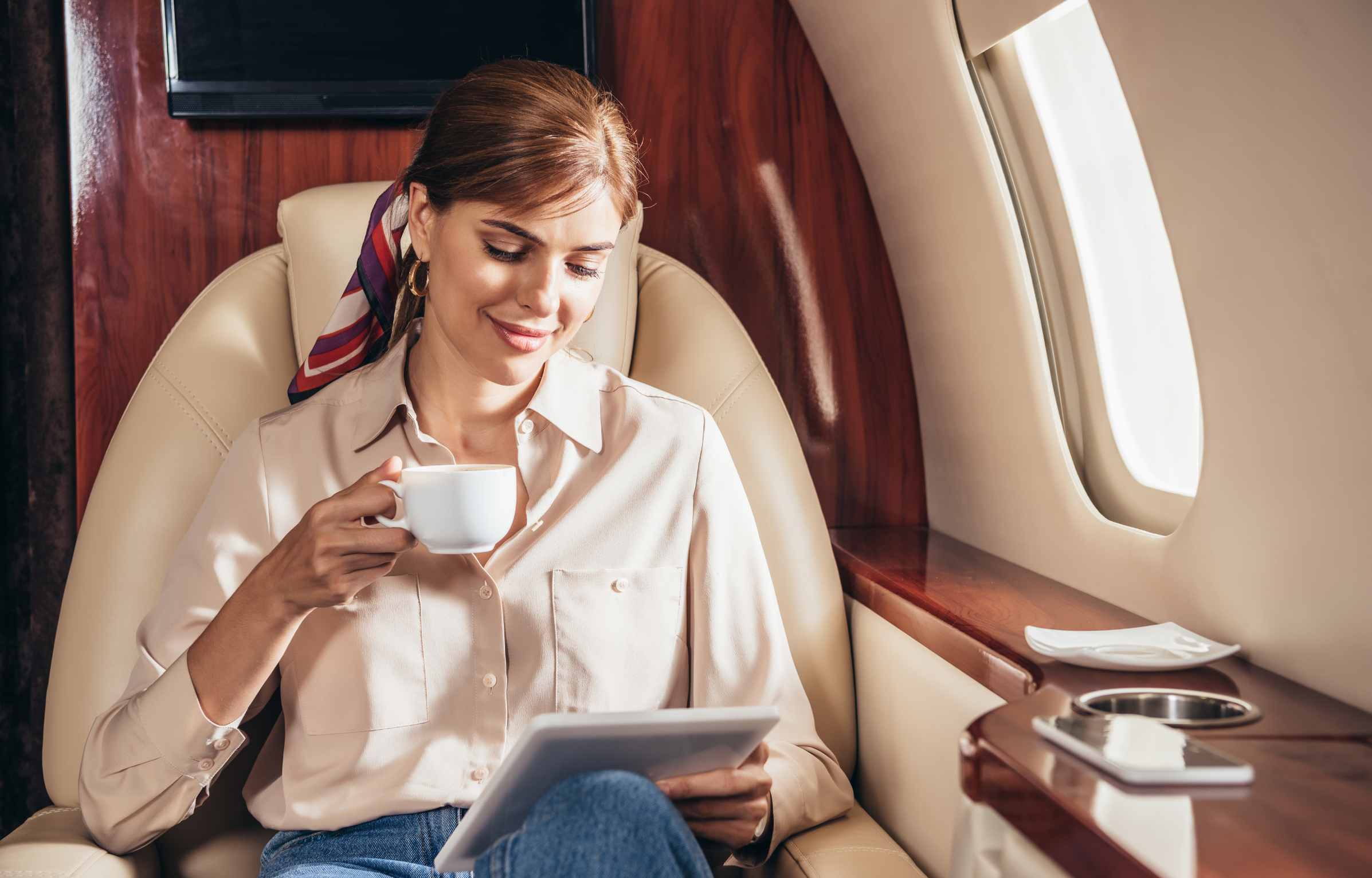 attractive woman in shirt using digital tablet in private plane