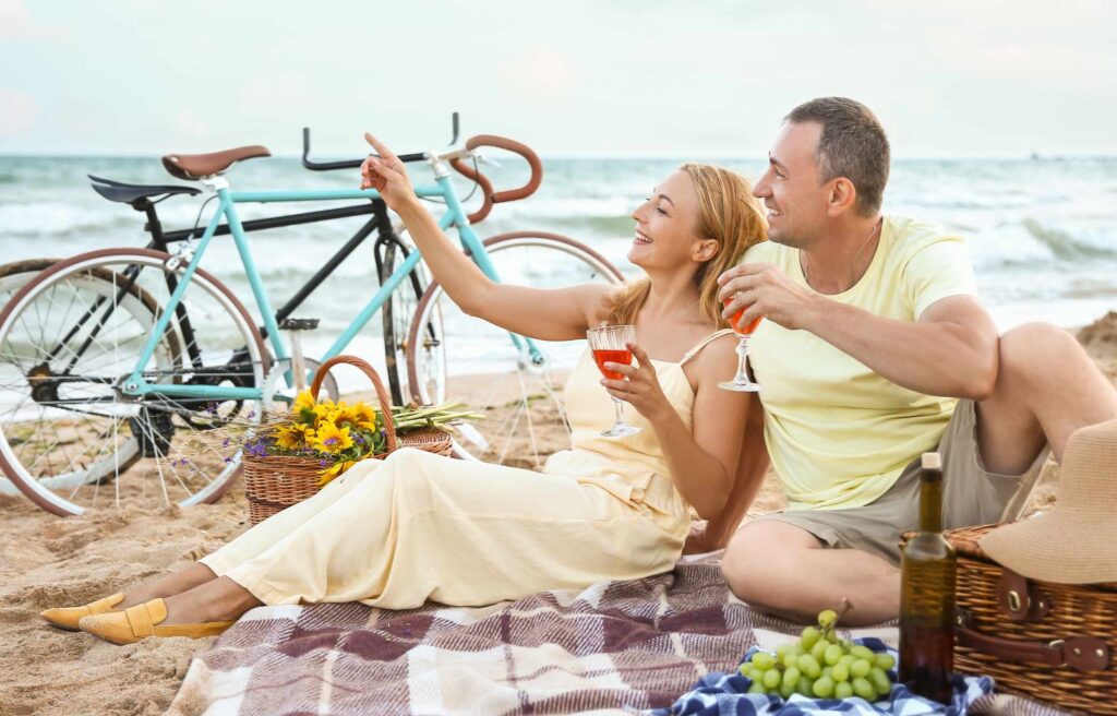 Mature couple having picnic near sea on summer day
