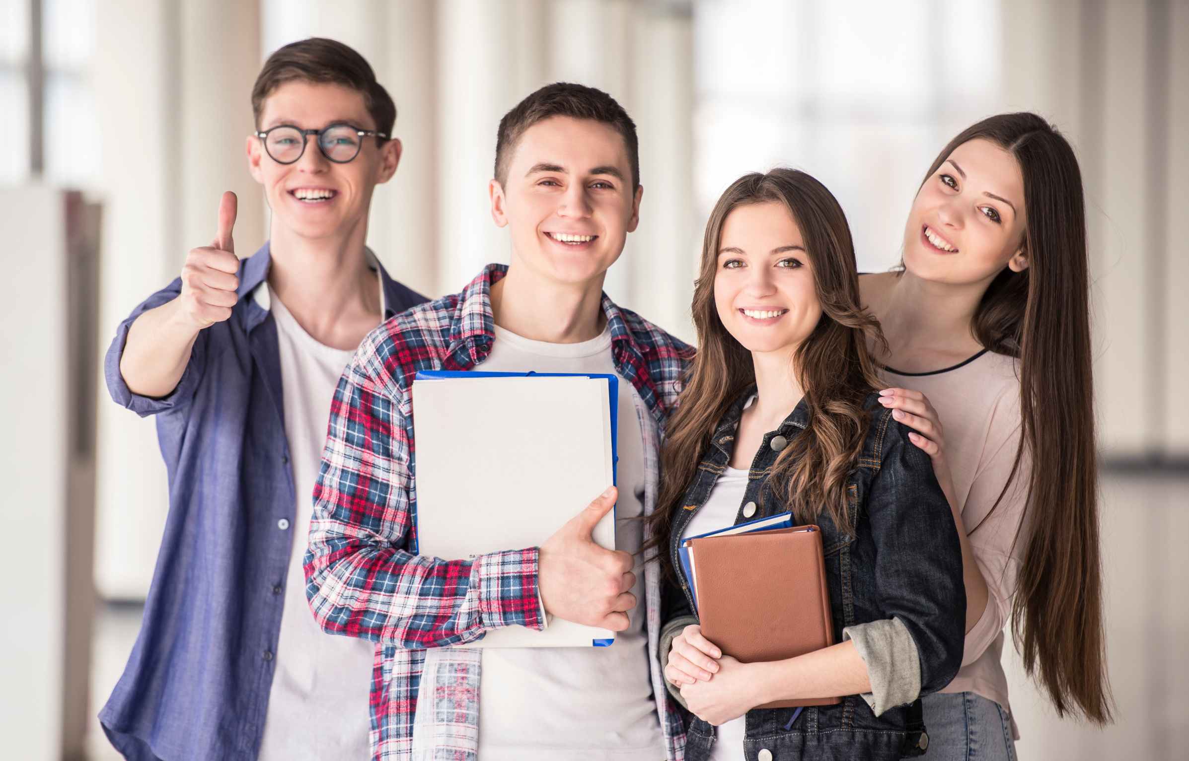 Happy Four College Students Standing and Holding Book