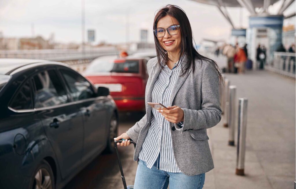 Happy caucasian woman traveller in airport terminal is taking a taxi