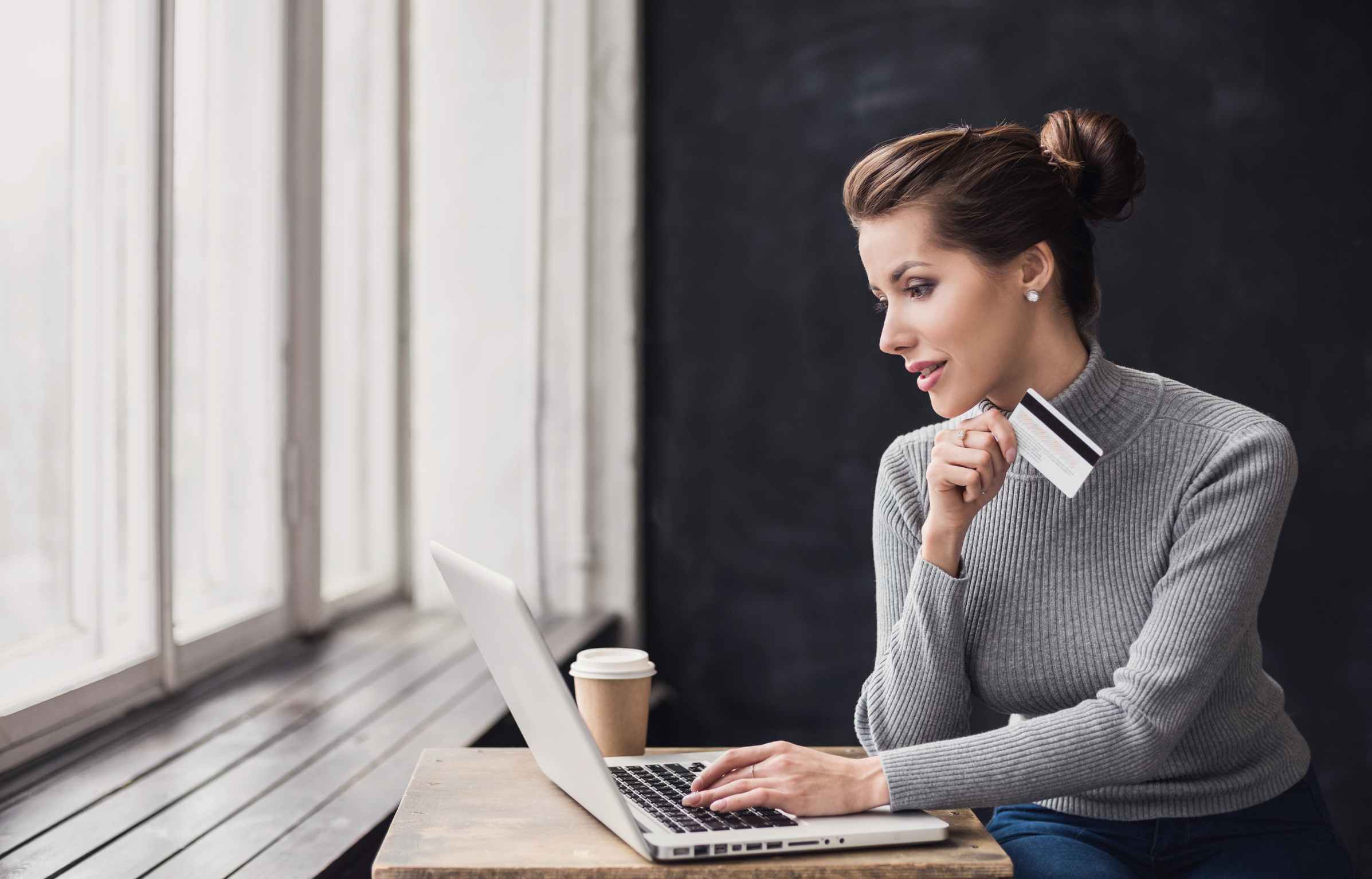 Young woman holding credit card and using laptop computer. Online shopping concept