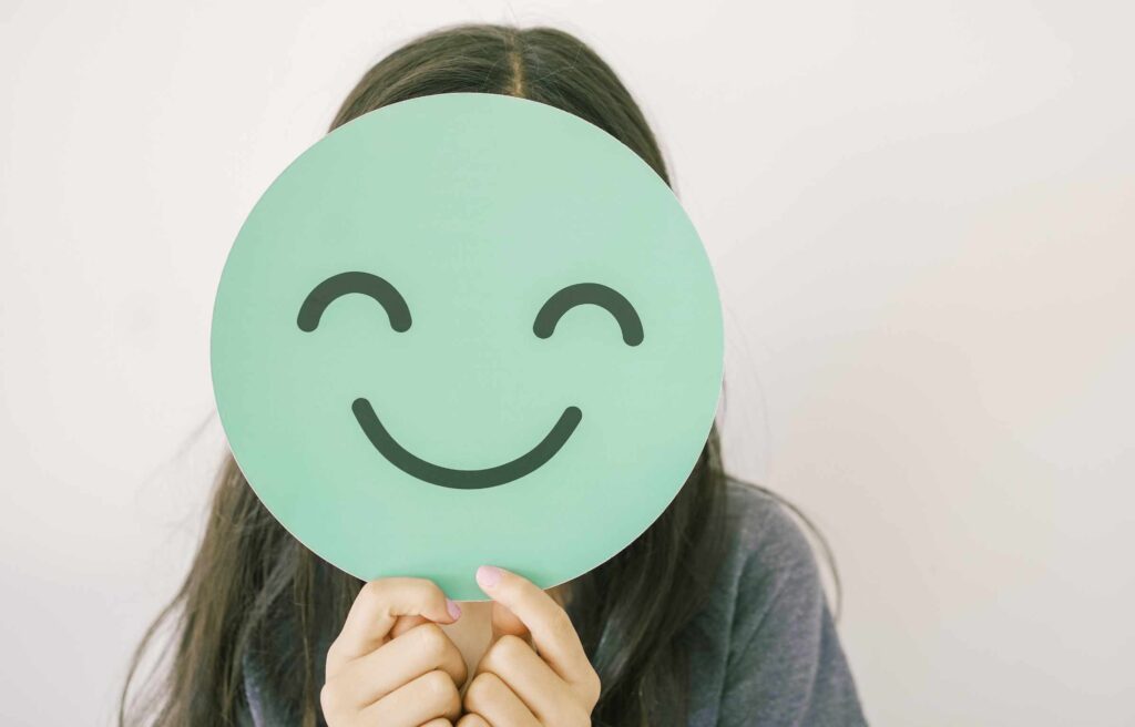 preteen girl holding green happy smile face cover her face, mental health assessment, child positive wellness, world mental health day concept