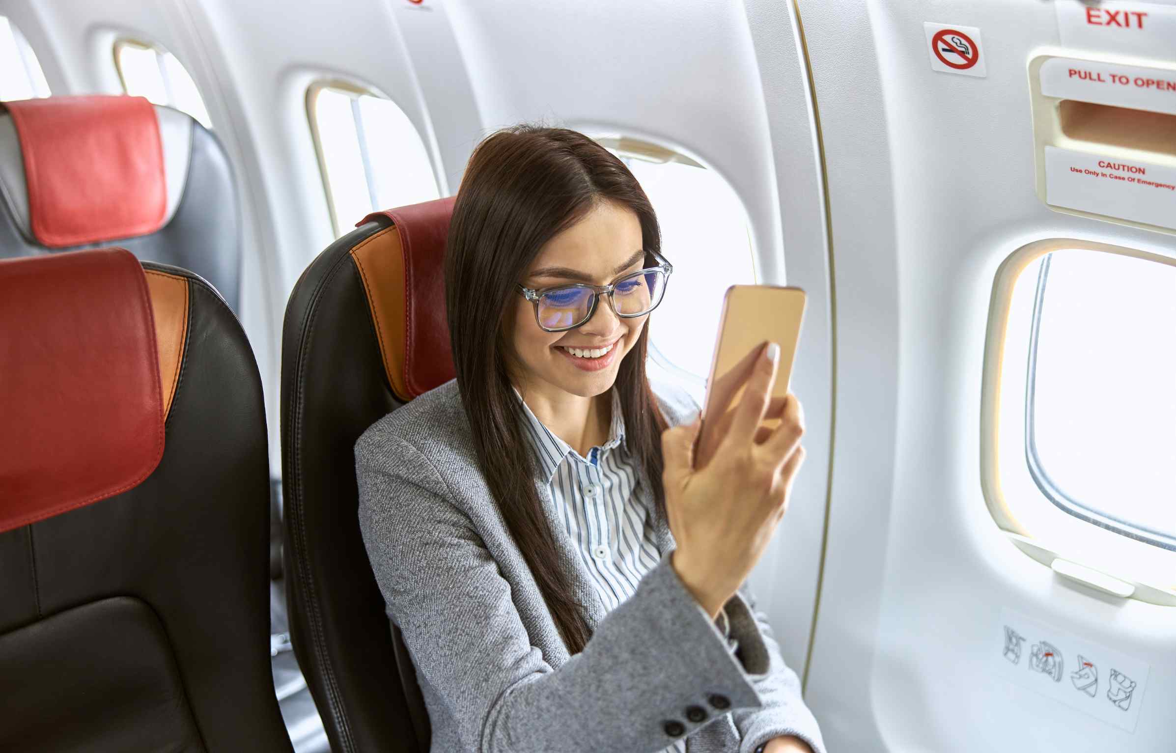 Business traveler using phone in flight showing delta business traveler program comfort
