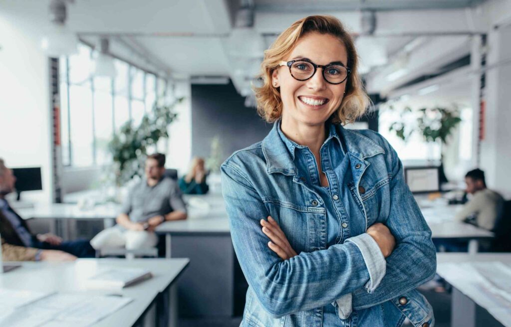 women smiling in a modern office setting symbolise employee financial well being and workplace satisfaction.