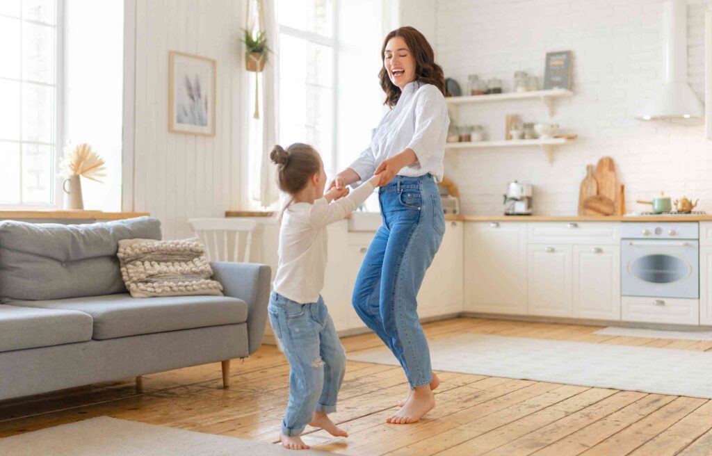 A mother dancing with her daughter in their new home, symbolizing joy after receiving relocation assistance for single mothers.