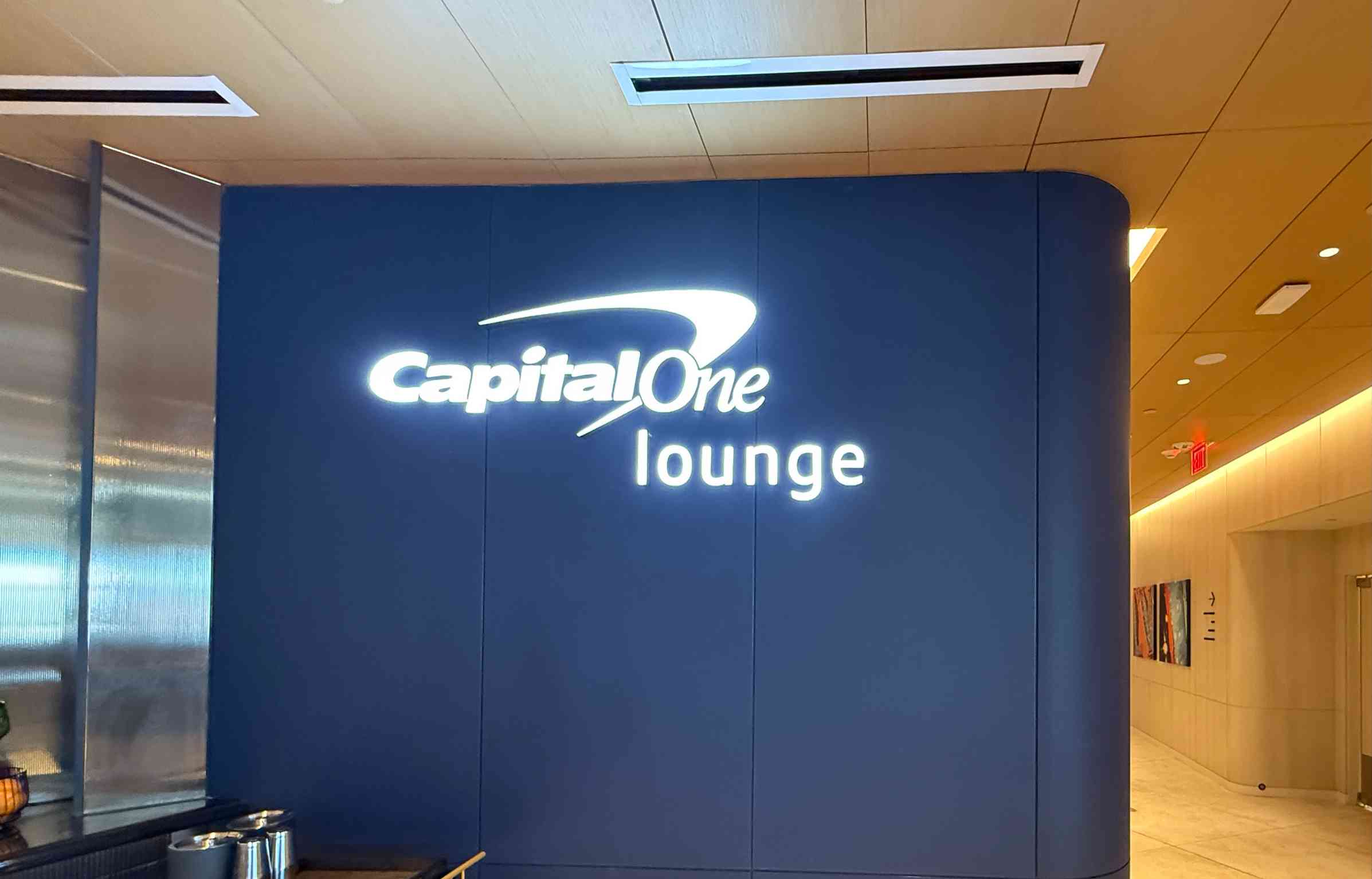 Illuminated Capital One Lounge logo on a deep blue wall near the entrance, creating a sleek and welcoming look inside Denver International Airport.