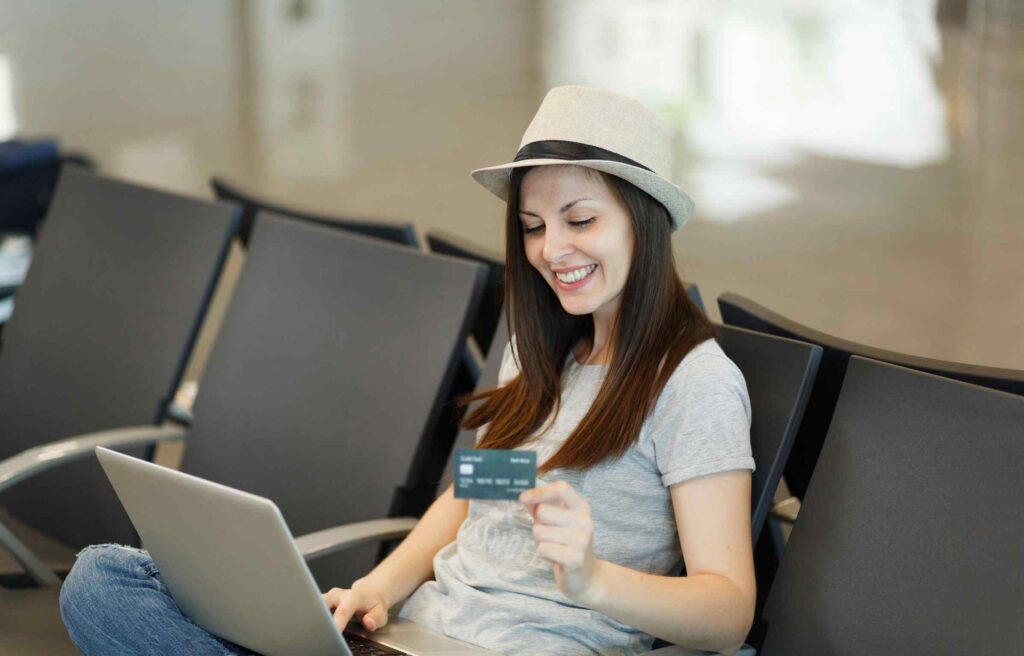 woman at airport using laptop and holding citi aadvantage executive world mastercard.