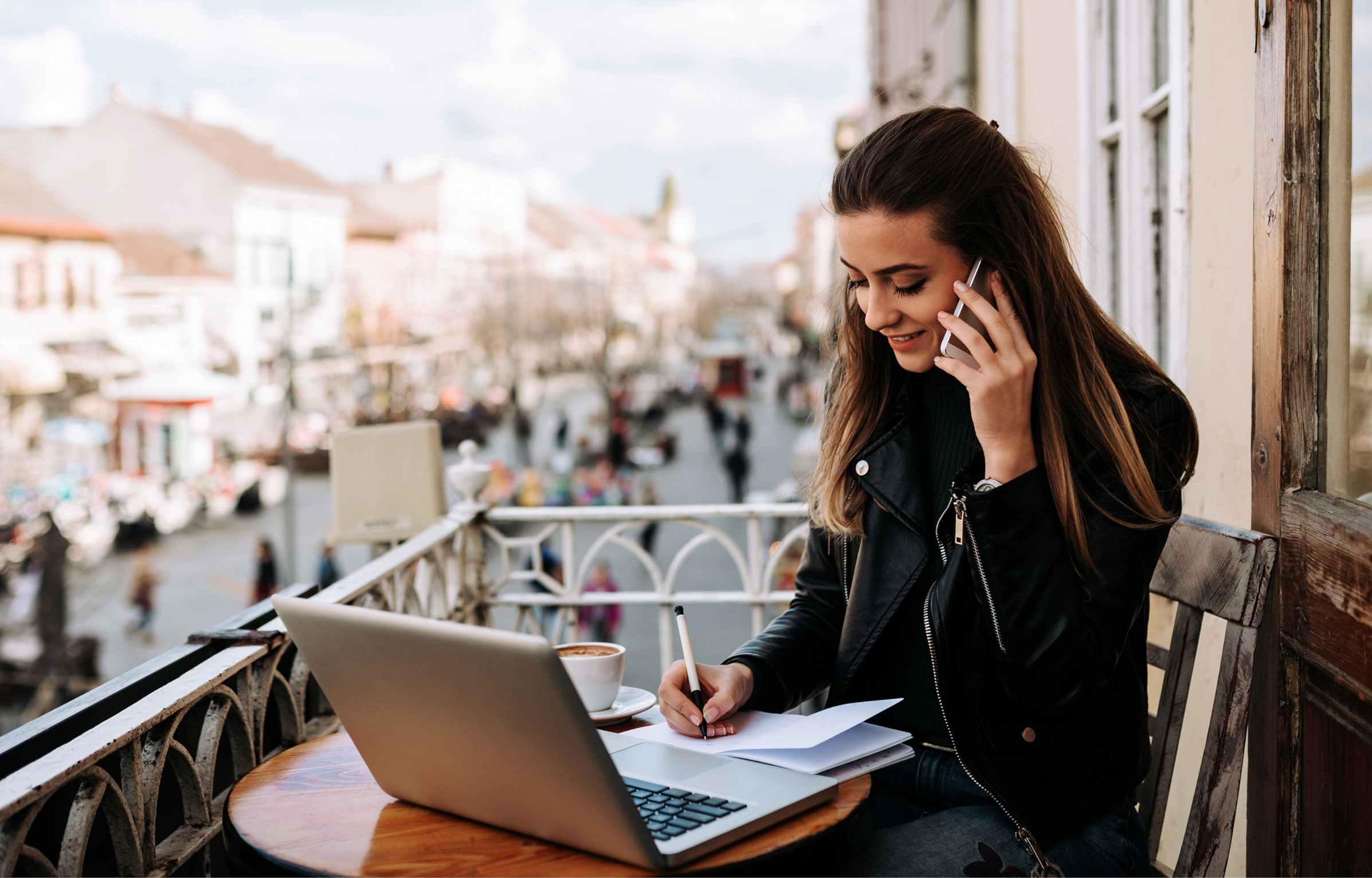 Young entrepreneur working outdoors in the cafe. Sitting on the balcony over the city street