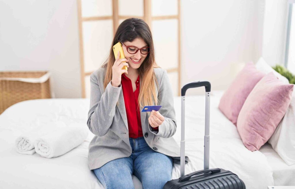 A woman in a world of hyatt hotel room holding a credit card, representing the benefits of world of hyatt credit card rewards.