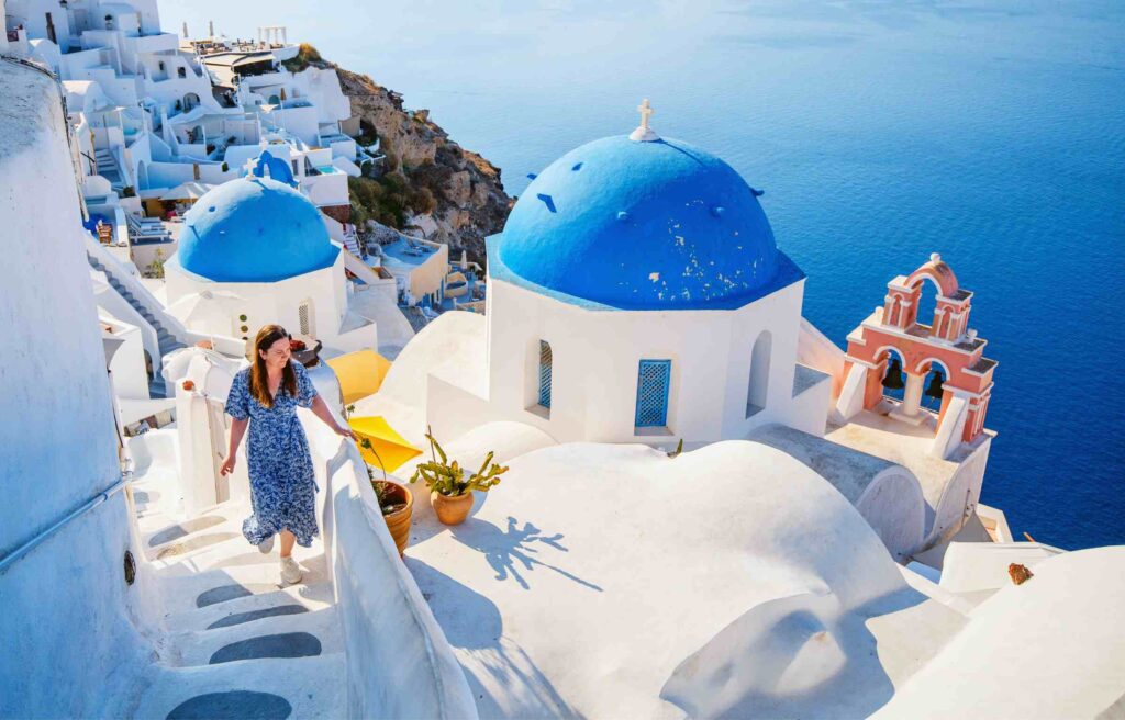 A woman walking in Santorini, Greece, shows the lifestyle offered by the greece digital nomad visa.