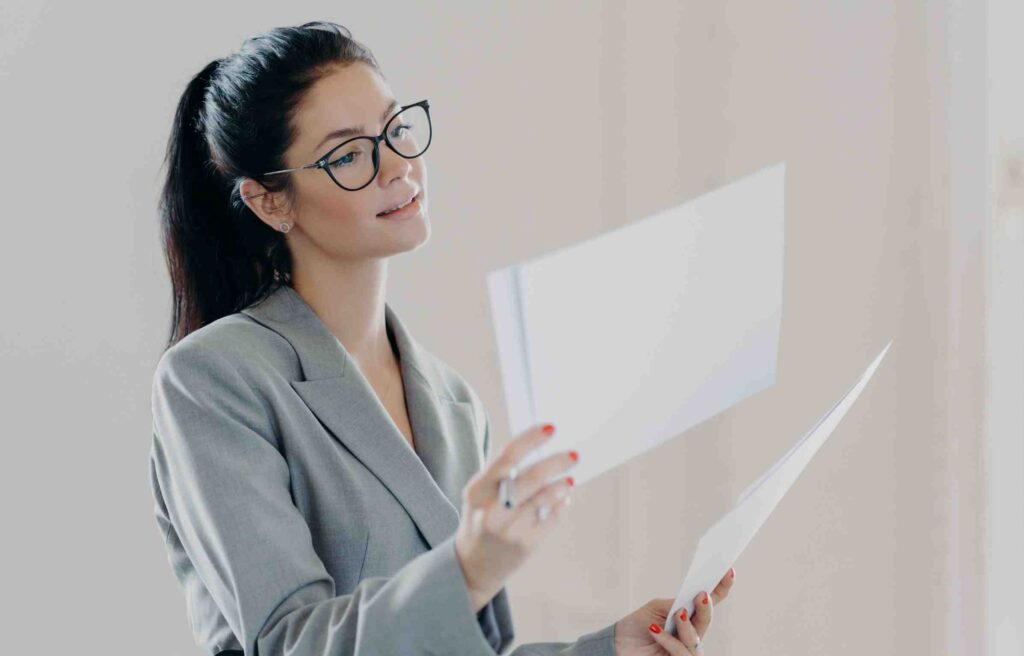 A woman in glasses is reading documents, reviewing a moving to chicago checklist.