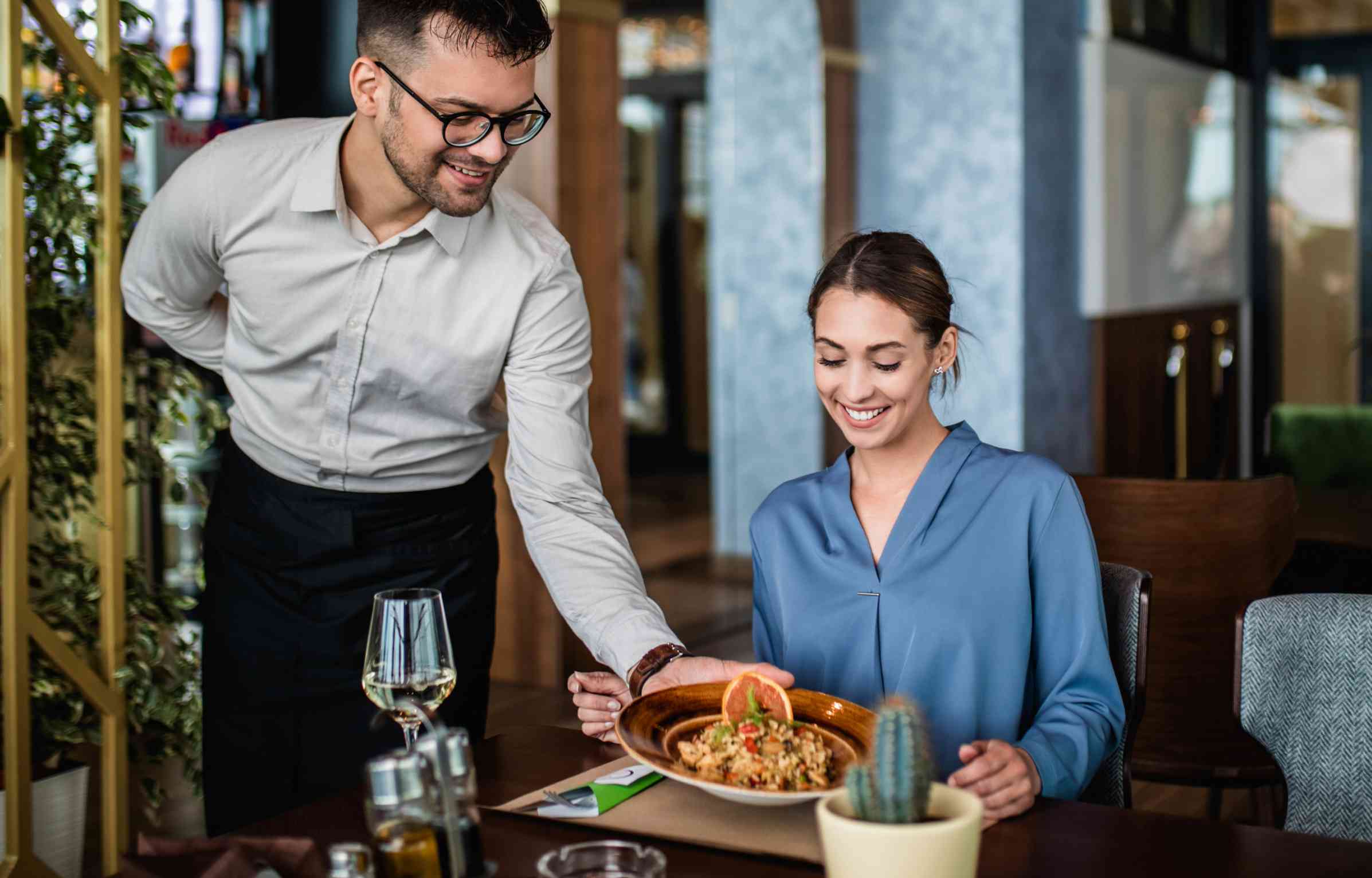 Woman smiling while paying at a restaurant with a credit card, representing earning miles through the aadvantage dining rewards program.
