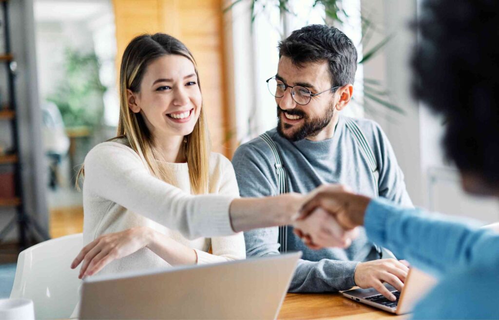 A woman shakes hands in her new office, showing a smooth transition with job relocation services.