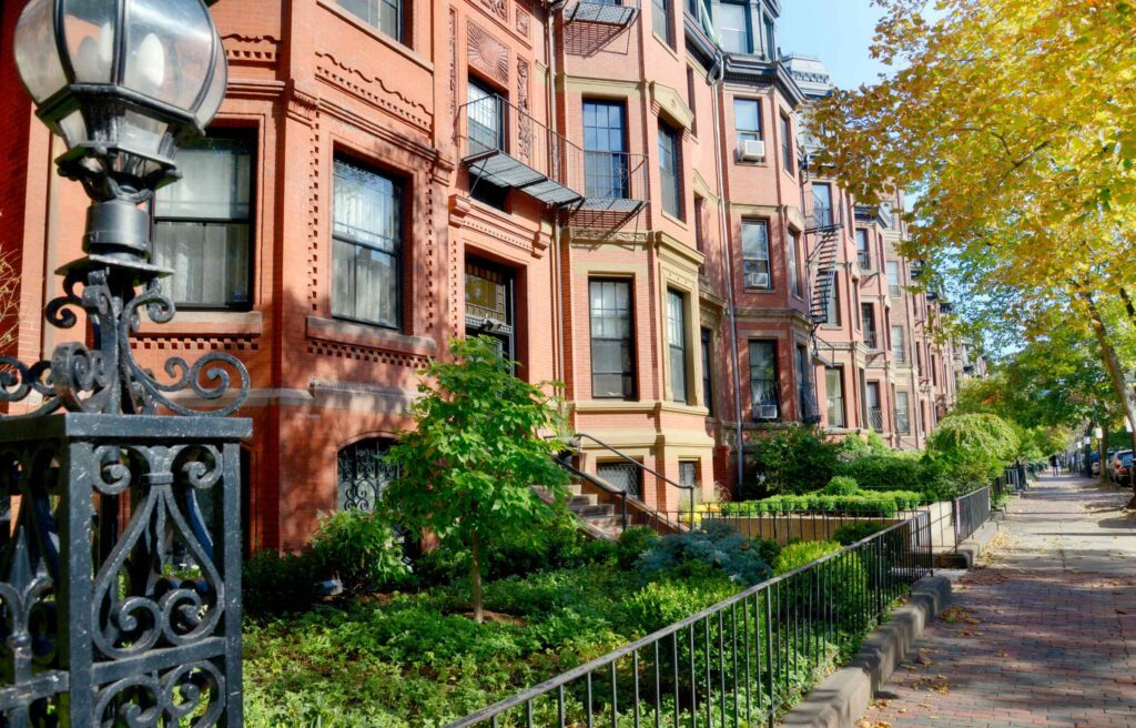Historic brownstone buildings along a tree-lined street in Boston’s Back Bay neighborhood.