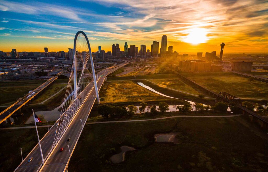 Dallas–Fort Worth skyline at sunset with the Margaret Hunt Hill Bridge in the foreground.