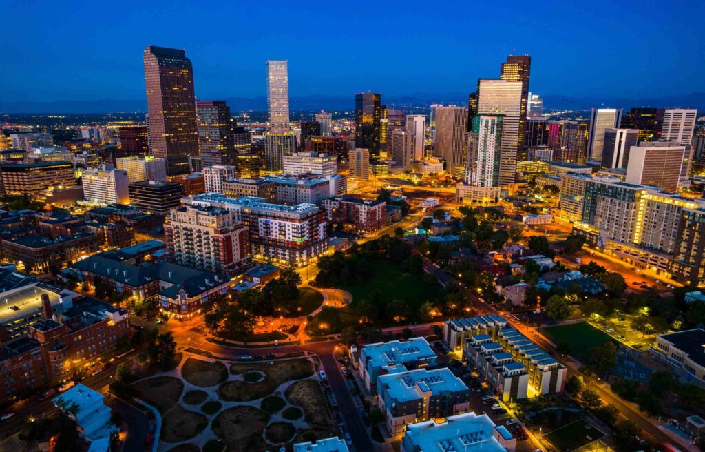 Denver Colorado downtown city skyline illuminated at night with modern high-rise buildings and streets below.