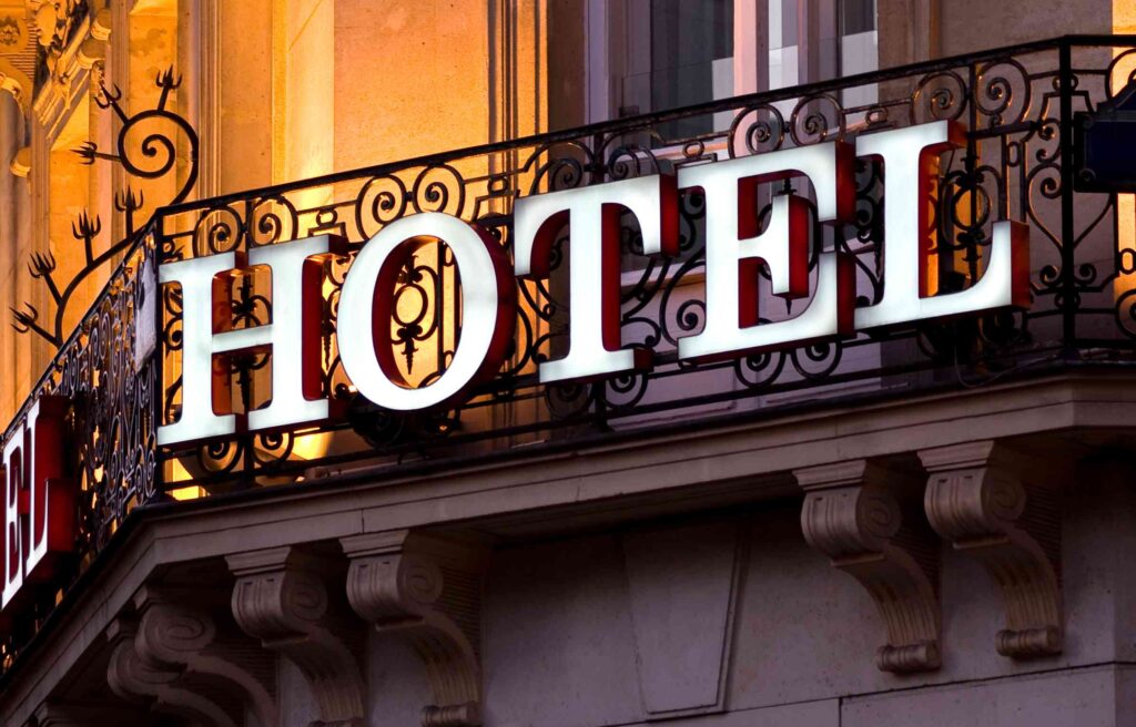 Illuminated hotel sign on an ornate balcony at night.
