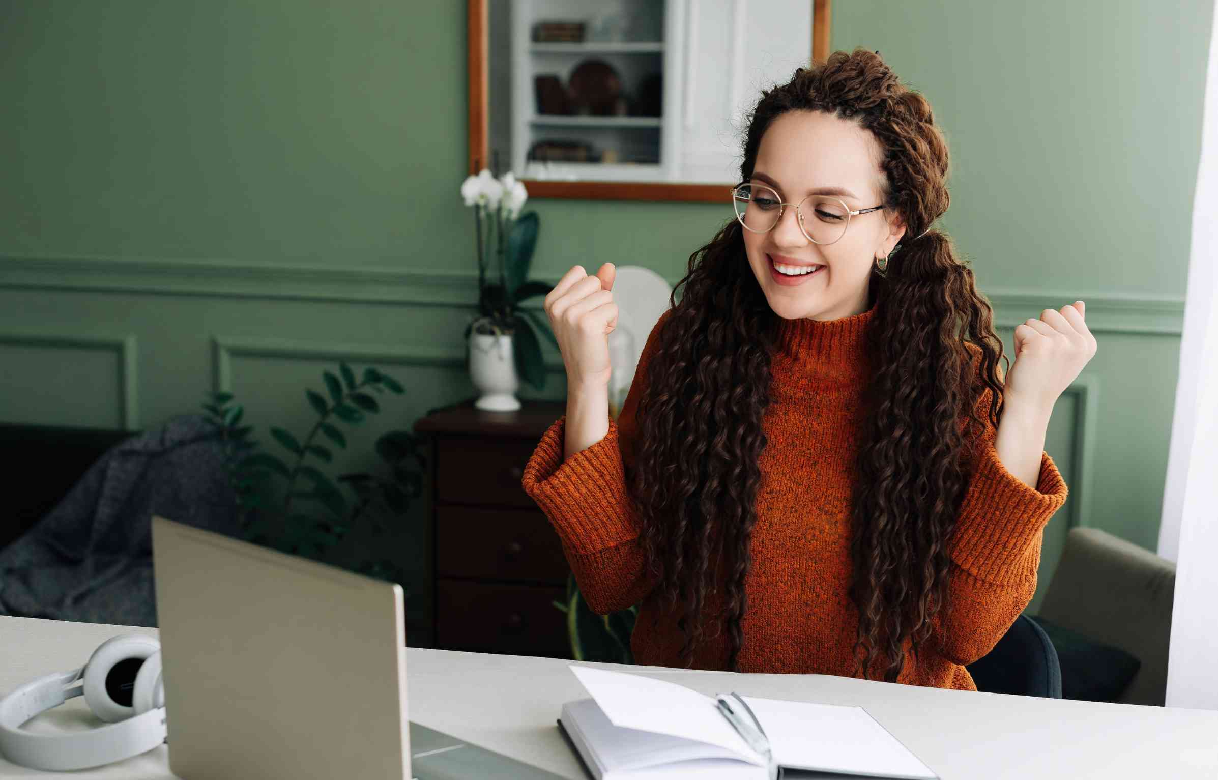 Happy student celebrating after completing a moving checklist while studying on a laptop at home.