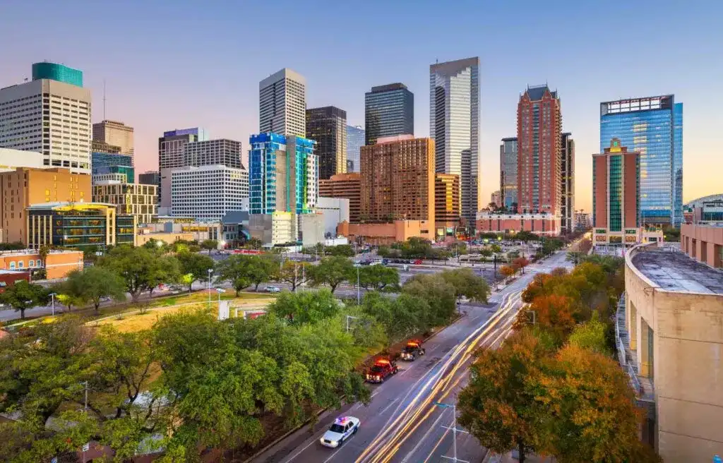 Downtown Houston Texas skyline at sunset with modern skyscrapers and tree-lined streets.
