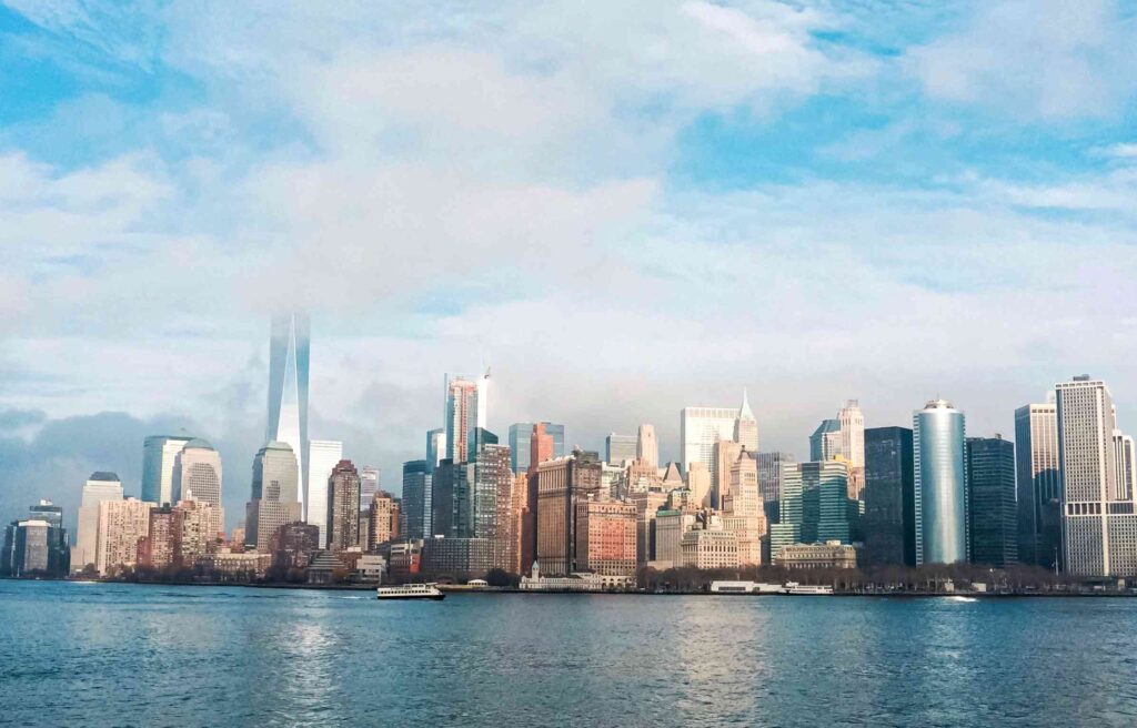 Panoramic view of the New York City skyline with skyscrapers rising above the waterfront on a clear day.