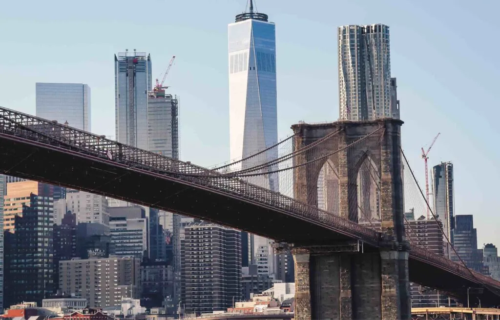Brooklyn Bridge with the New York City skyline and One World Trade Center in the background.
