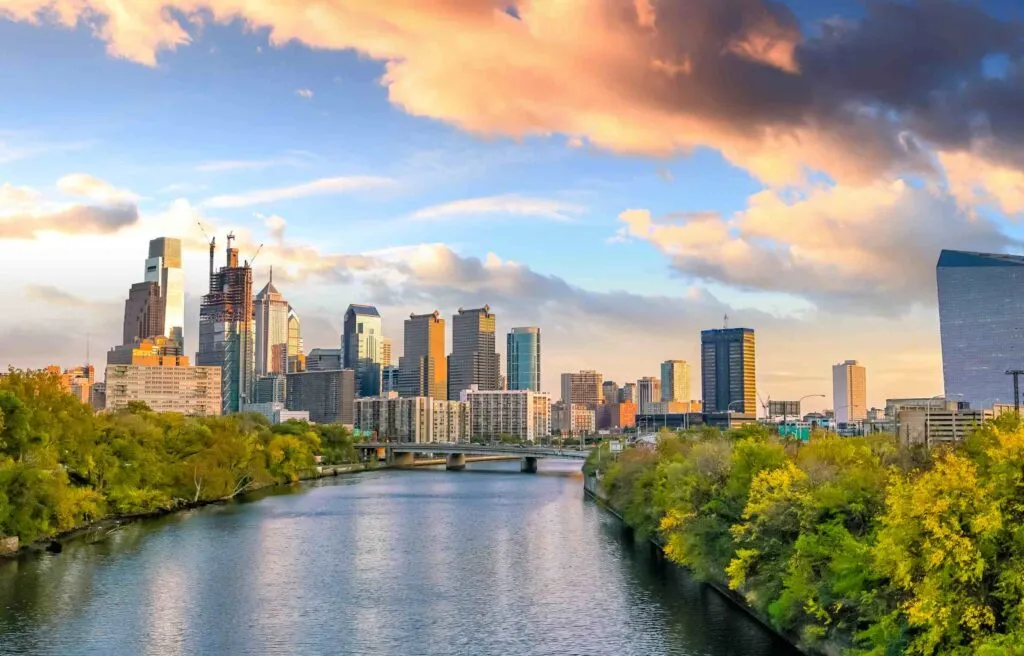 Philadelphia Pennsylvania skyline with tall buildings at sunset viewed across the Schuylkill River.
